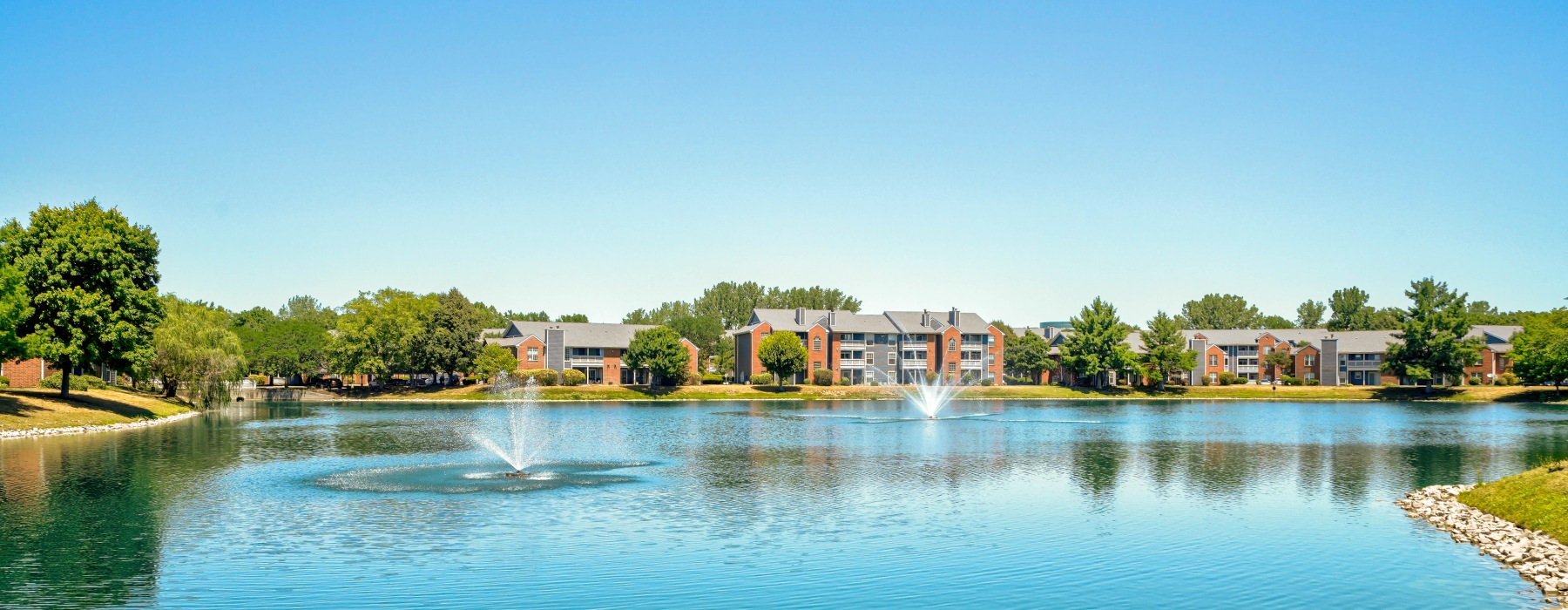 tranquil lake with a fountain that the apartment complex overlooks