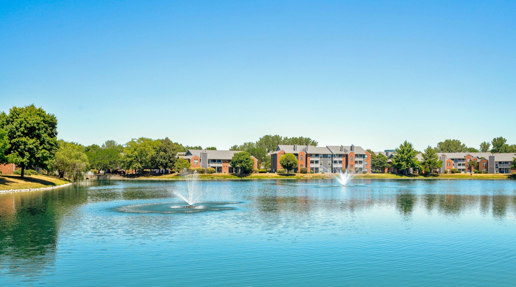 tranquil lake with a fountain that the apartment complex overlooks