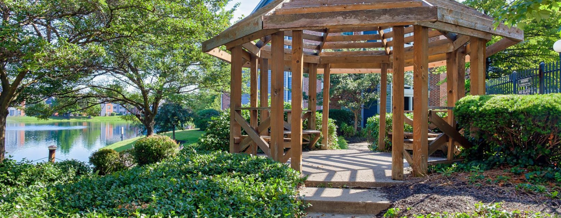 a wooden gazebo with a pond and trees